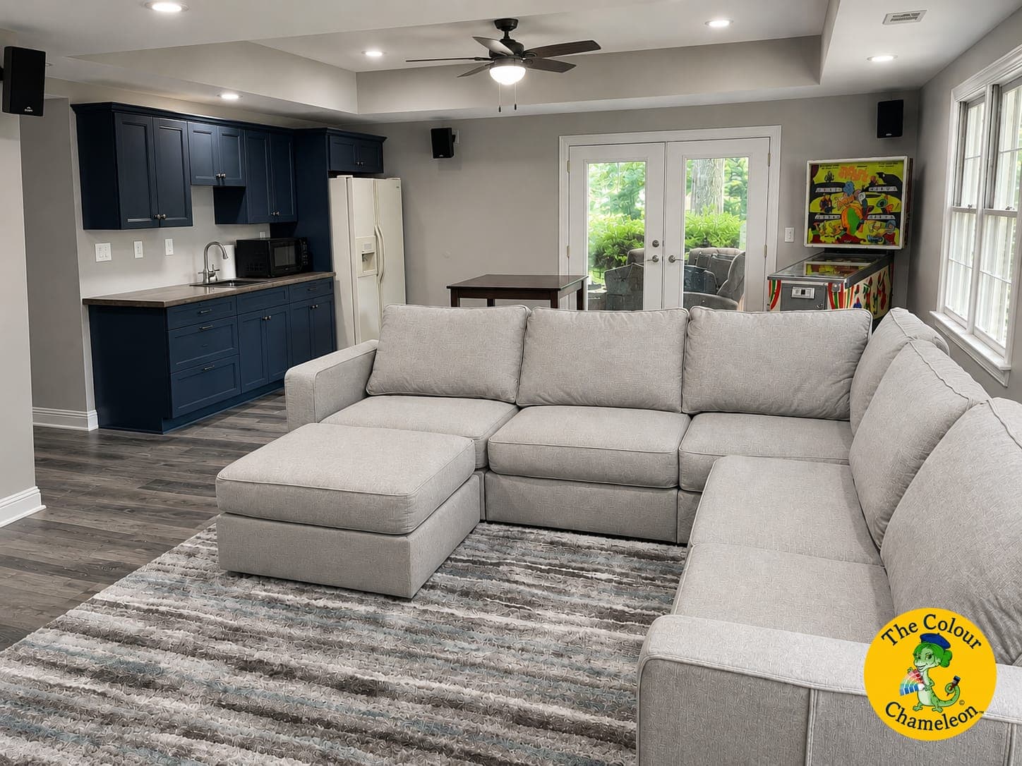 The same basement painted light warm gray, with navy blue cabinetry and wood-look flooring