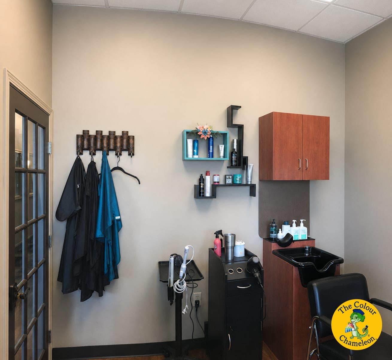 A salon suite with greige walls, a wood-toned wall cabinet and black wall shelves