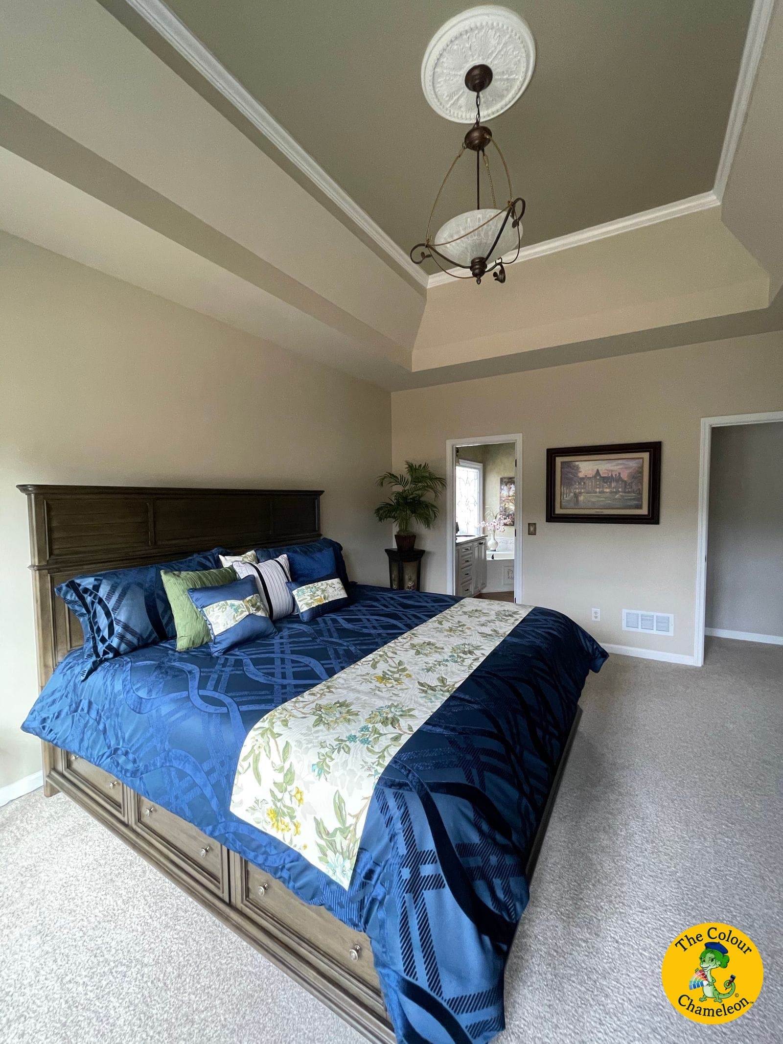The same bedroom repainted in a warm greige, with the tray ceiling picked up and navy bedding