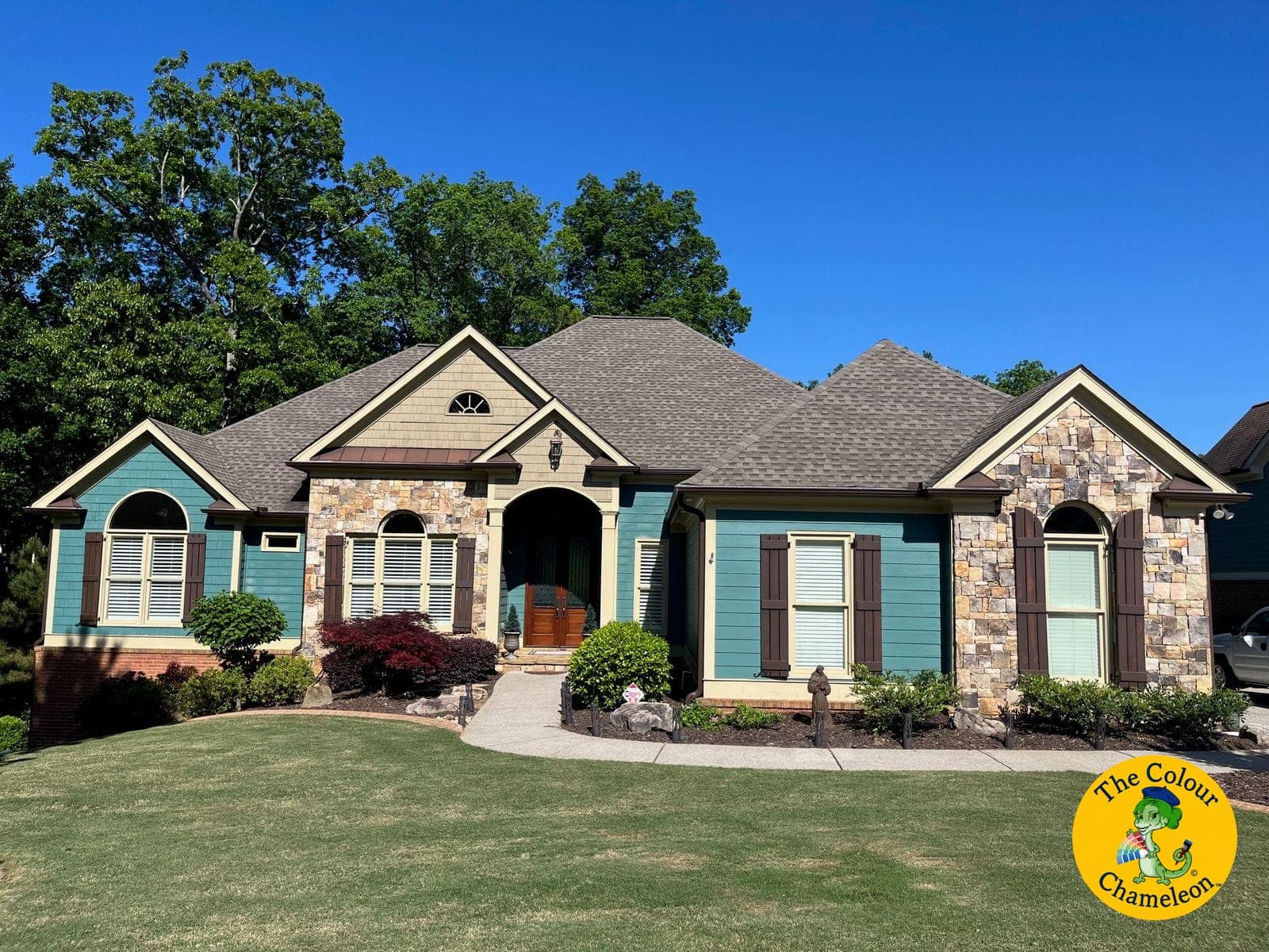 A ranch-style house with turquoise siding, butter-yellow trim and stone accents