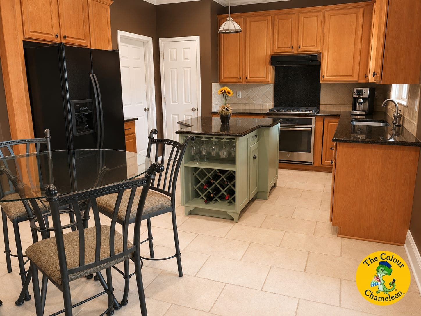A kitchen with golden oak cabinets, brown walls, a sage green island and black appliances
