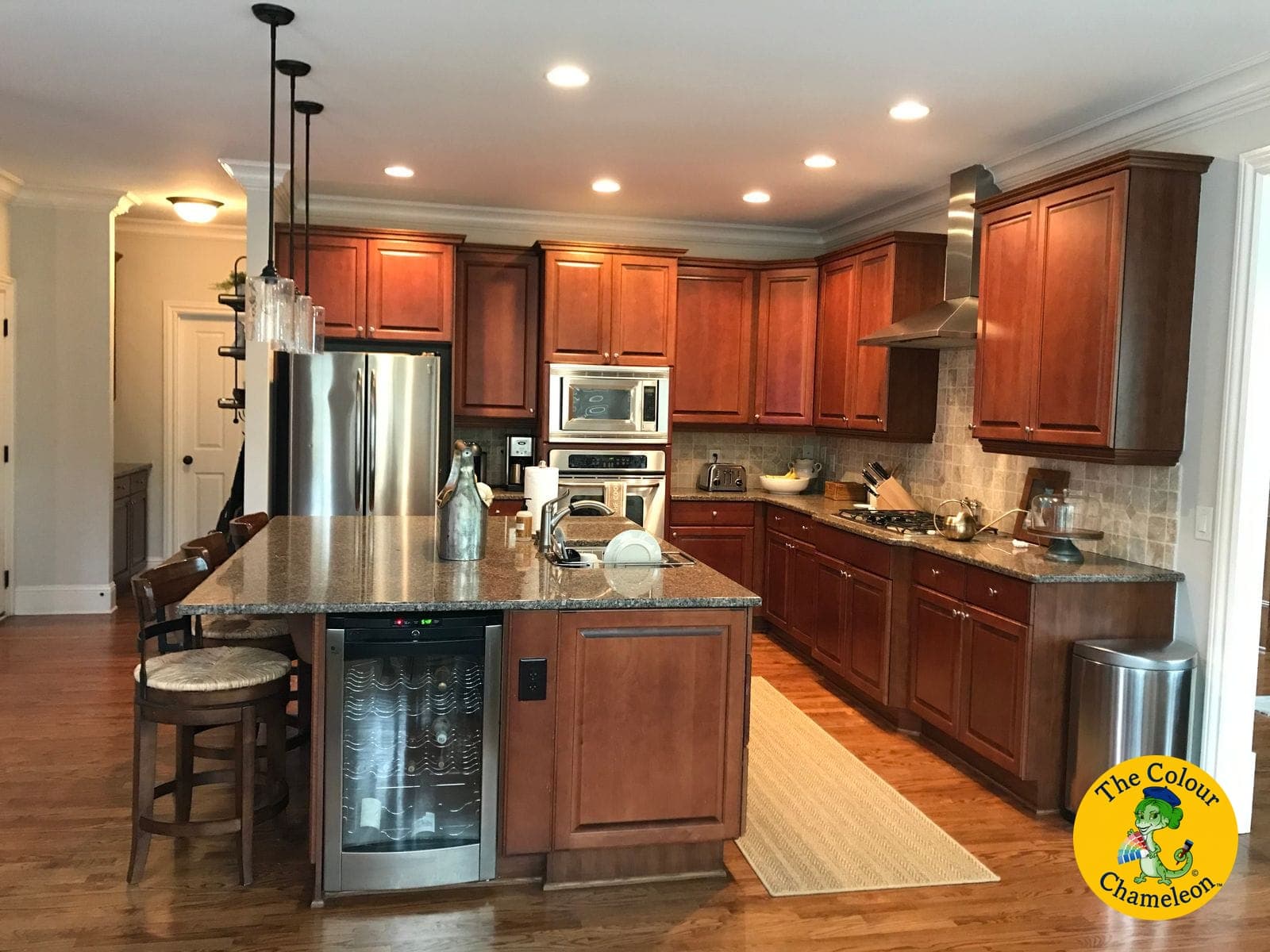 A kitchen with cherry-stained cabinets, granite counters and a large island with a wine fridge