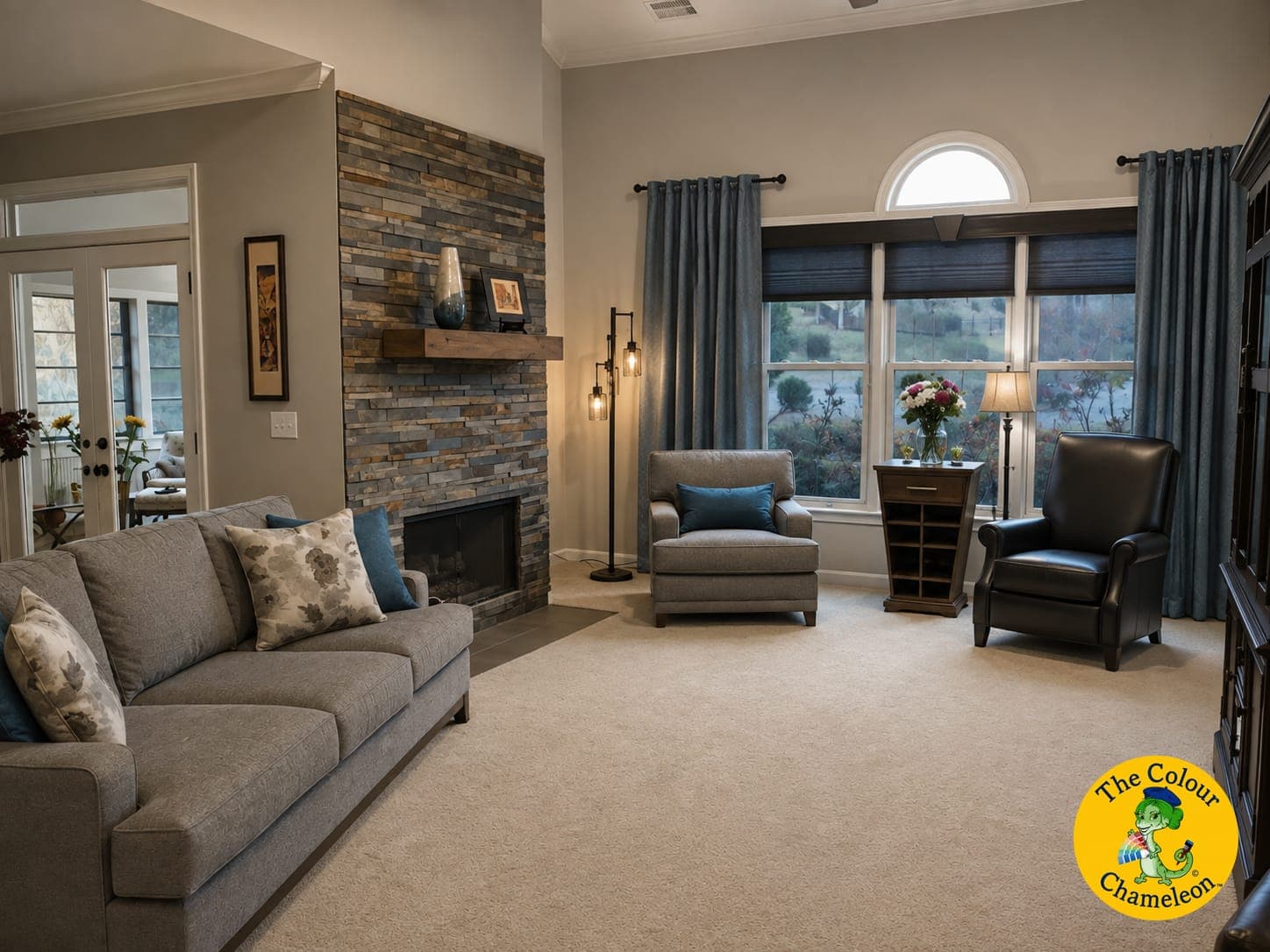 The same living room in a soft greige, with a stacked-stone fireplace and warm gray furnishings